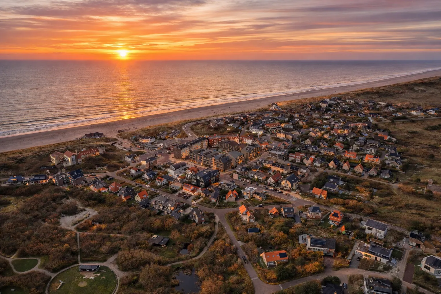 Bergen aan Zee bij zonsondergang, gezien over de duinen
